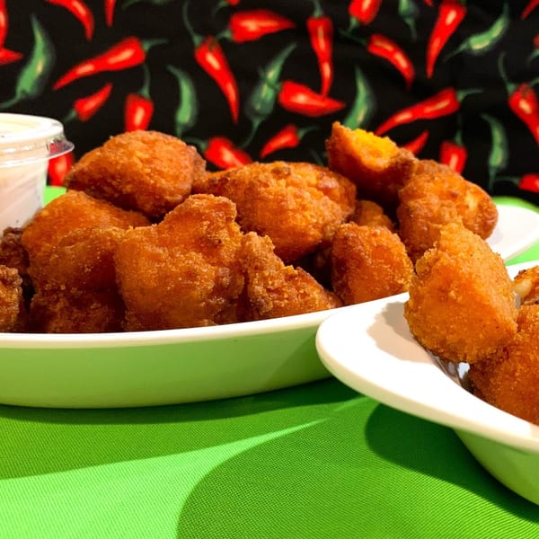 Golden-brown fried cheese curds in white bowls, with a chili pepper patterned background.