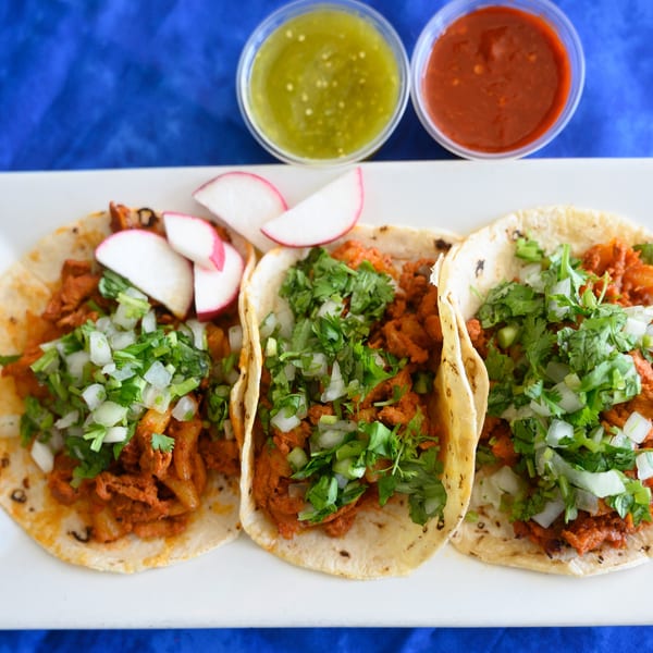 Three Papa Joe's Mexican Restaurant tacos with meat, cilantro, onions, radishes, and two salsas.