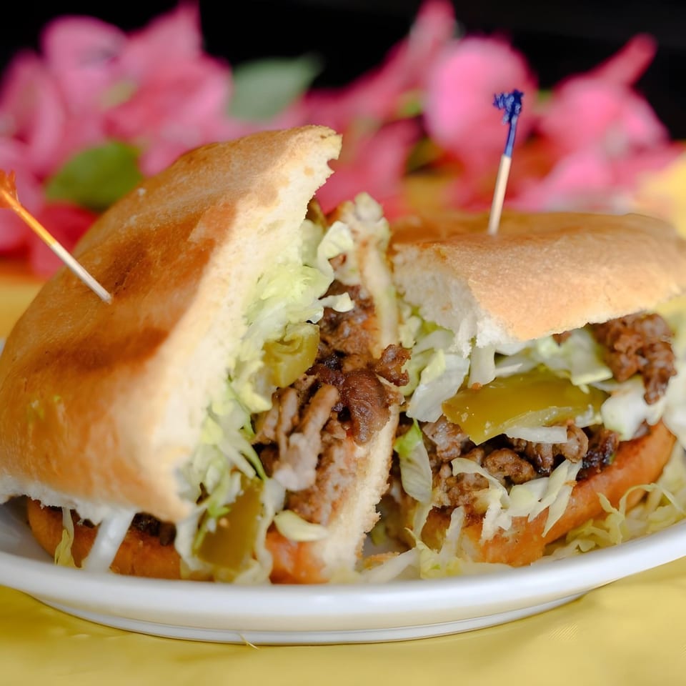A Papa Joe's Mexican Restaurant torta, cut in half, filled with meat, lettuce, and jalapeños.